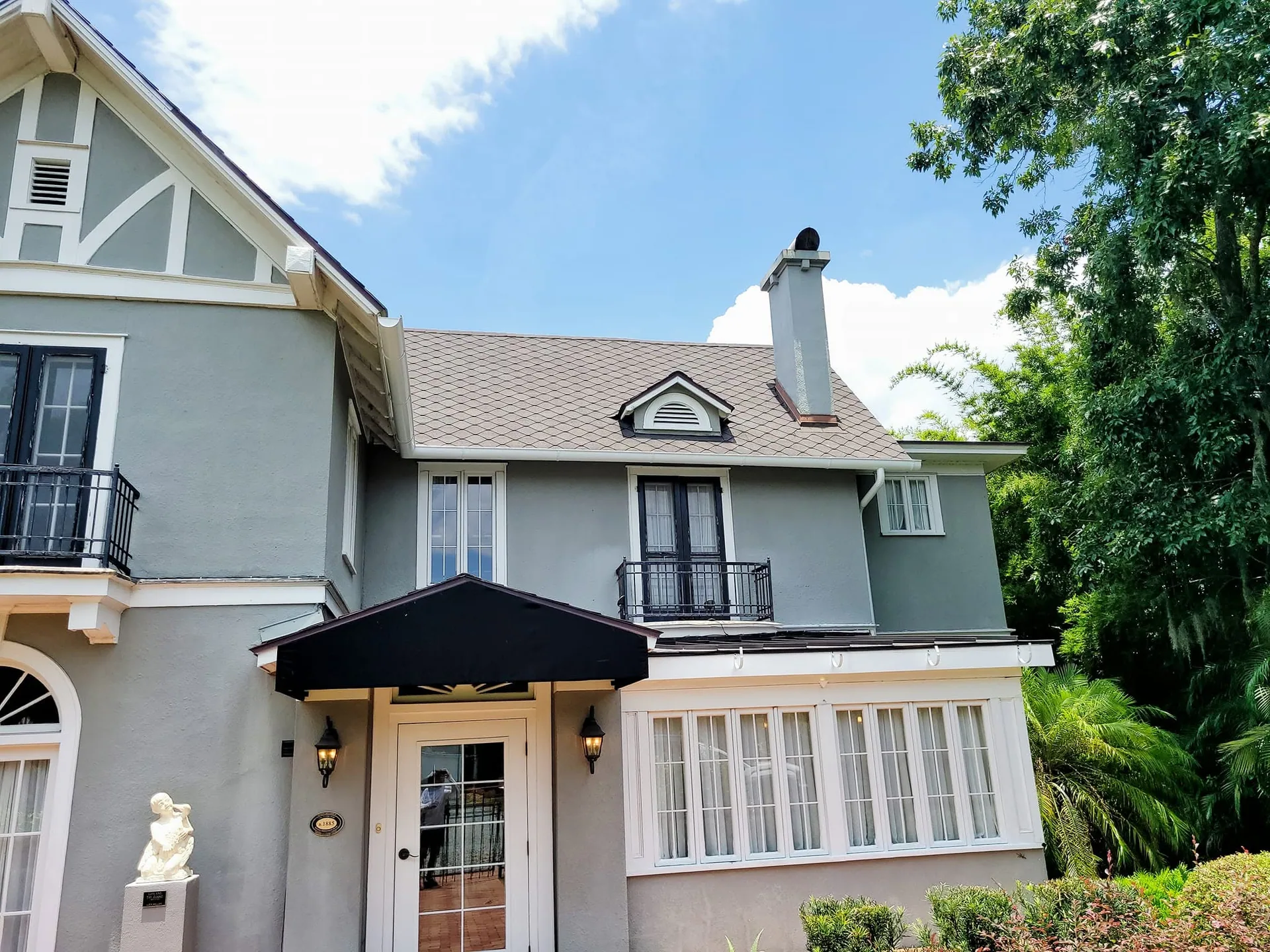 Gray stucco tudor home black awning entry dormer chimney, Sanford